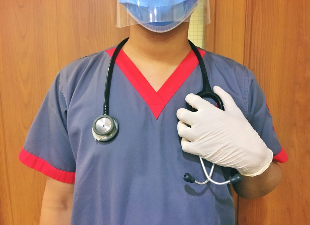 Person in a mask and gloves with a stethoscope around their neck
