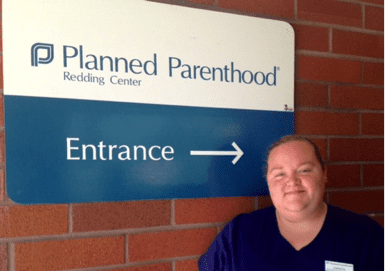 Woman smiling in front of Planned Parenthood entrance